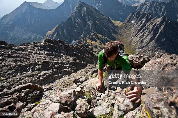 a man scrambles up a gully on the crestone needle in the sangre de cristo mountains, colorado. - sangre stock pictures, royalty-free photos & images