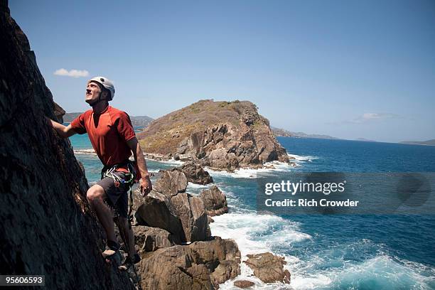 a man looks up while traditionally climbing a new route along a remote cay in the us virgin islands. - us virgin islands stock pictures, royalty-free photos & images