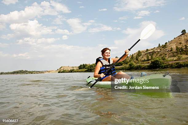 a young teenage girl smiles while paddling her kayak through the cool waters of the yellowstone rive - girl rowing boat photos et images de collection