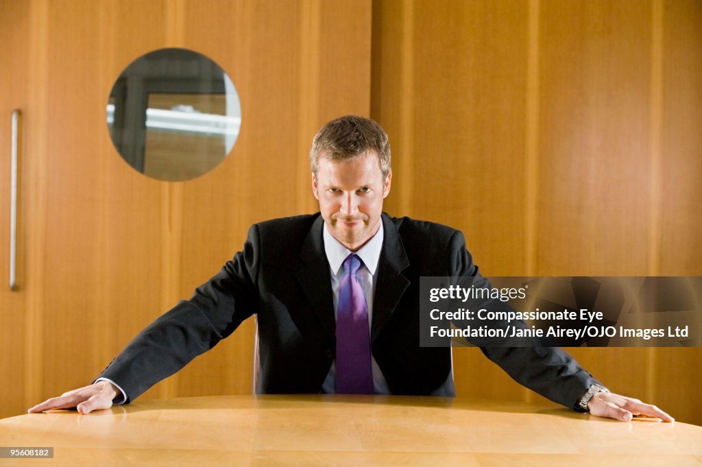 Man in suit sitting with arms on table