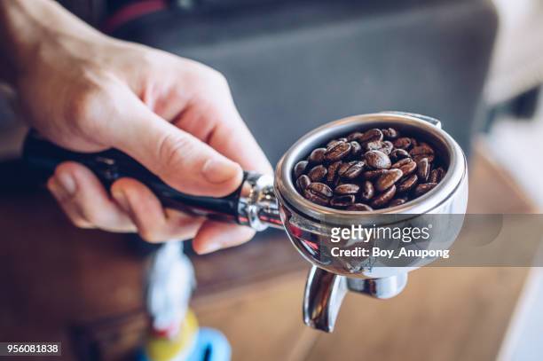 barista holding a bottomless portafilter before making a fresh coffee. - bean stock-fotos und bilder