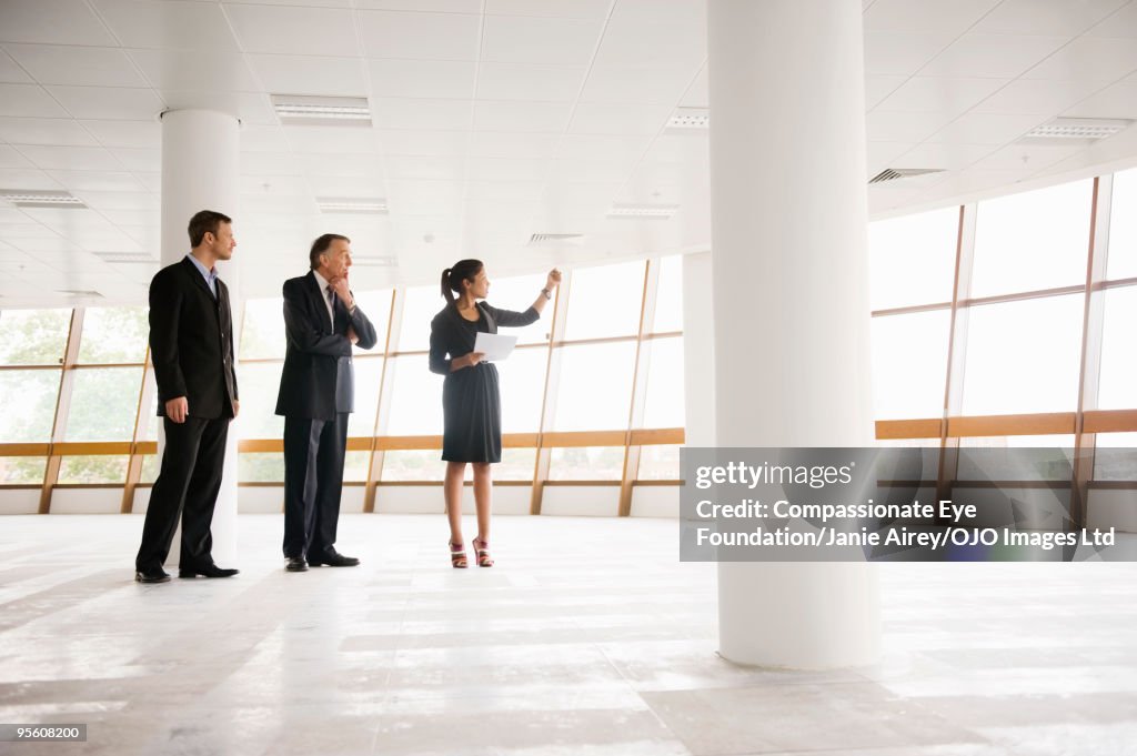 Three professionals standing in large open room 