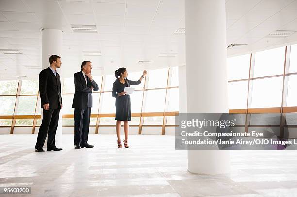 three professionals standing in large open room  - commercial property imagens e fotografias de stock