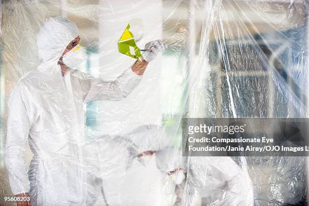 three people in masks and white suits - pandemie stock pictures, royalty-free photos & images