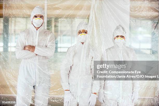 three people in surgical masks and white suits - pandemie 個照片及圖片檔