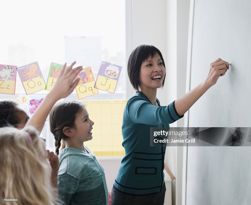 Teacher writing on blackboard with students