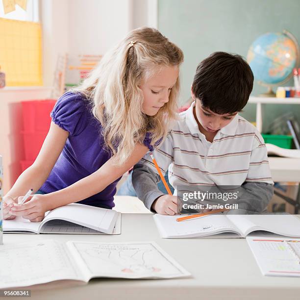 young girl cheating off of boy in classroom - text book stockfoto's en -beelden
