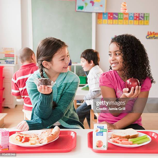 young girls comparing school lunches - lunchpauze stockfoto's en -beelden