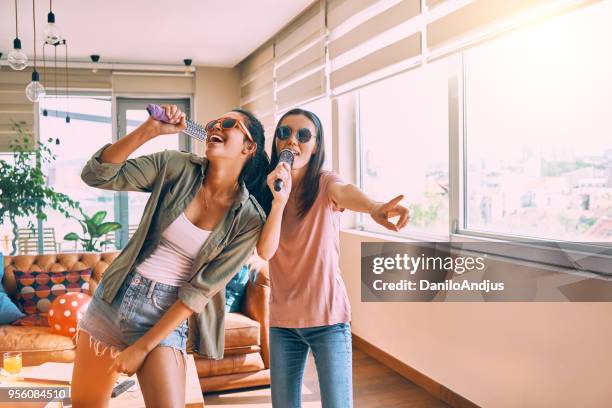 two friends having fun singing together - karaoke stock pictures, royalty-free photos & images