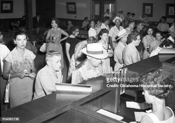 Photograph of dozens of people waiting in line inside the Capitol Hill State Bank, Oklahoma City, Oklahoma, summer 1960. The bank had just been due...