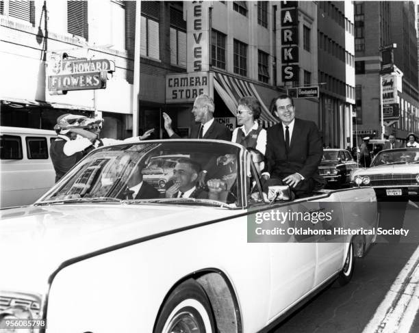 Photograph of Bud Wilkinson and Richard M Nixon riding on the back seat of a convertible in a parade, Oklahoma City, Oklahoma, March 2, 1964.