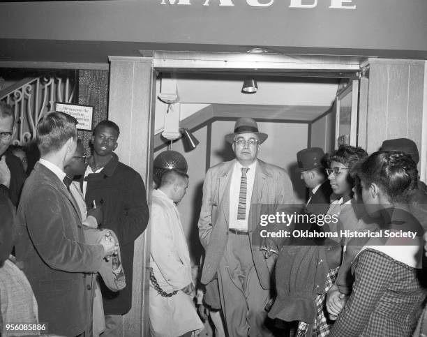 Photograph of Father Robert McDole at far left; Taylor 'Skippy' Johnson, to the left of the door wearing a black coat; and Earl Temple among a crowd...