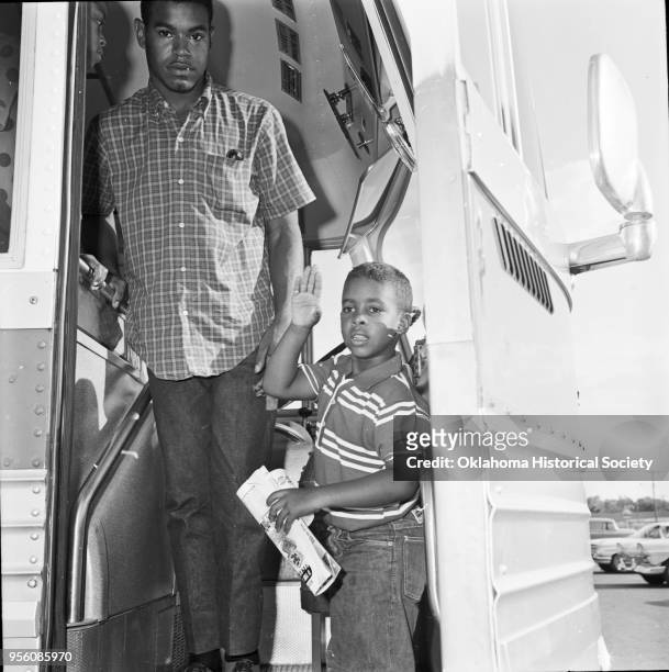 Photograph of a young man and boy boarding a bus at Douglass High School on their way to a National NAACP Convention , Oklahoma City, Oklahoma,...