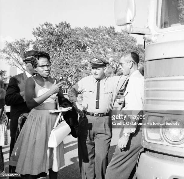 Photograph of Clara Luper, Willie James, a bus driver and a reporter standing outside a chartered bus at Douglass High School, Oklahoma City,...