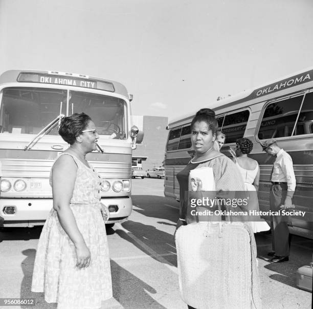 Photograph of, from left to right, Opaline Watkins, Janice Watkins, a Reporter, Clara Luper , and a bus driver who are waiting to board a chartered...