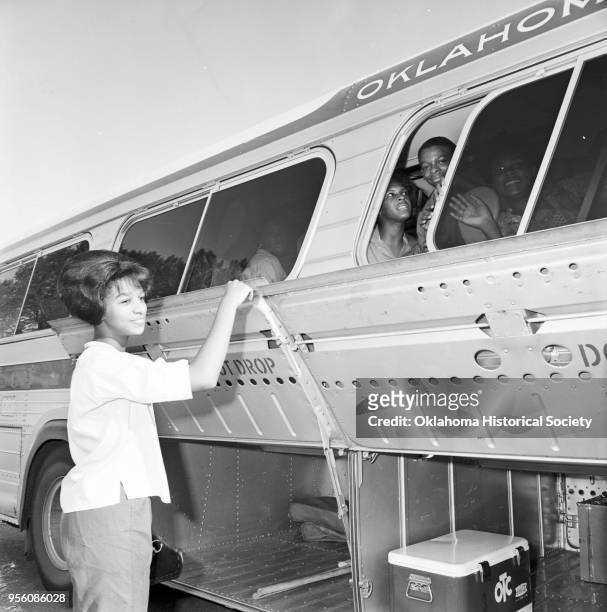 Photograph of Peggy Cosby loading her luggage on a chartered bus at Douglass High School on the way to a National NAACP Convention , Oklahoma City,...