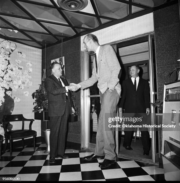 Photograph of 'Tall Man' Henry Hite shaking hands with an unidentified man at Glen's Hickory Inn at 2815 NW 10th Street, Oklahoma City, Oklahoma, mid...