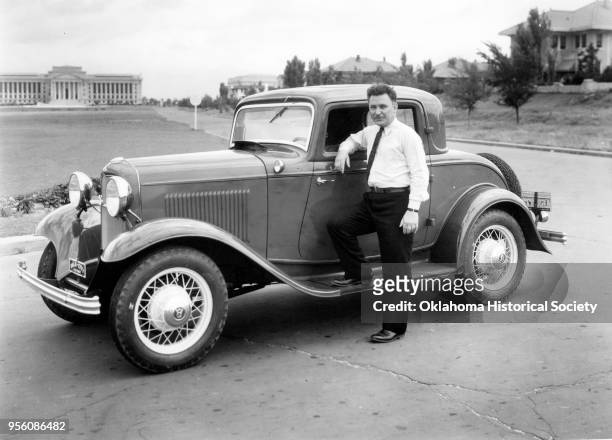 Photograph of Wiley Post on the running board of a car parked at Northwest 18th and Lincoln Boulevard, in front of the Oklahoma State Capitol,...