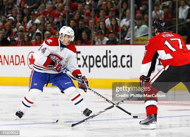 Tomas Plekanec of the Montreal Canadiens plays the puck across the blueline against Filip Kuba of the Ottawa Senators during their NHL game at...