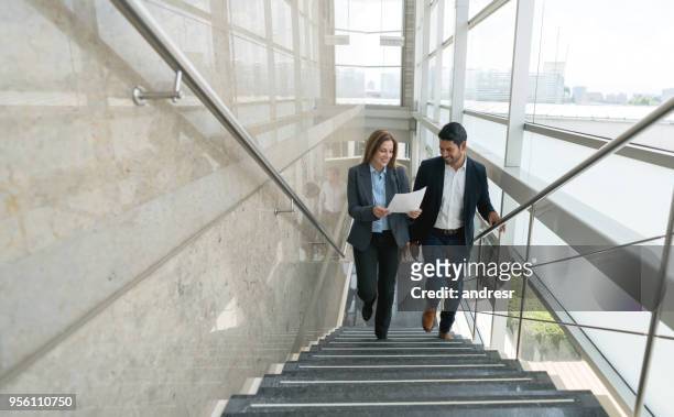 business partners walking up the stairs to the office looking at a document very satisfied - staircase stock pictures, royalty-free photos & images