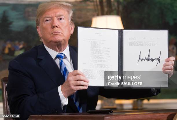 President Donald Trump signs a document reinstating sanctions against Iran after announcing the US withdrawal from the Iran Nuclear deal, in the...