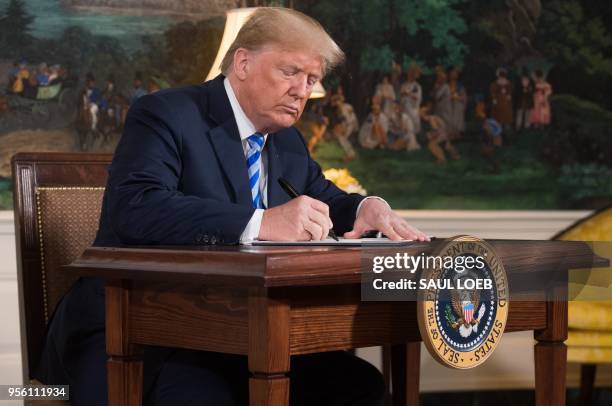 President Donald Trump signs a document reinstating sanctions against Iran after announcing the US withdrawal from the Iran Nuclear deal, in the...