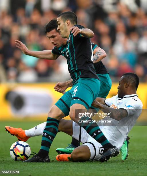 Jordan Ayew of Swansea City is tackled by Oriol Romeu and Steven Davis of Southampton during the Premier League match between Swansea City and...