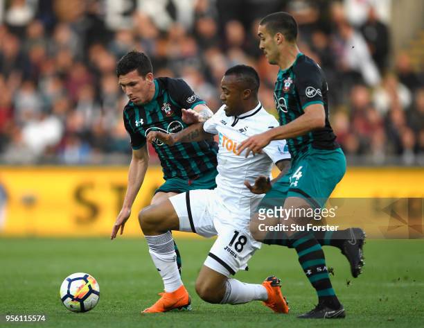 Jordan Ayew of Swansea City is tackled by Oriol Romeu and Steven Davis of Southampton during the Premier League match between Swansea City and...