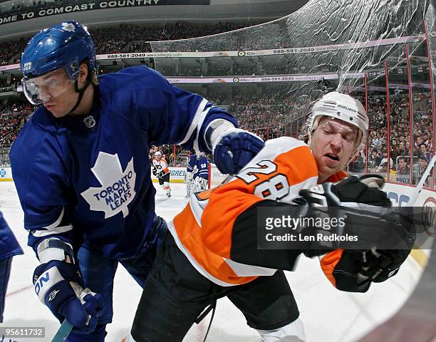 Garnet Exelby of the Toronto Maple Leafs checks Claude Giroux of the Philadelphia Flyers into the corner boards on January 6, 2010 at the Wachovia...
