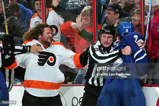 Scott Hartnell of the Philadelphia Flyers is separated by linesman Don Henderson from Garnet Exelby of the Toronto Maple Leafs late in the third...