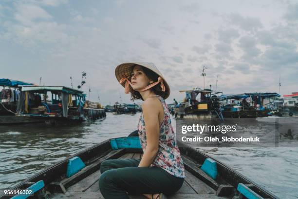 Mulher cavalgando no barco através do delta do Mekong e o mercado flutuante