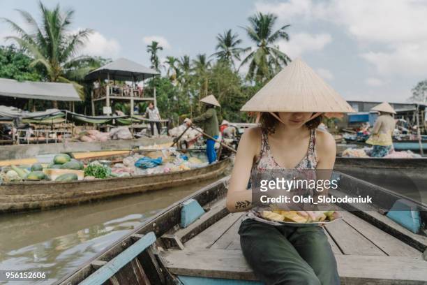 woman riding on boat and eating pineapple  through mekong delta and floating market - hot vietnamese women stock pictures, royalty-free photos & images