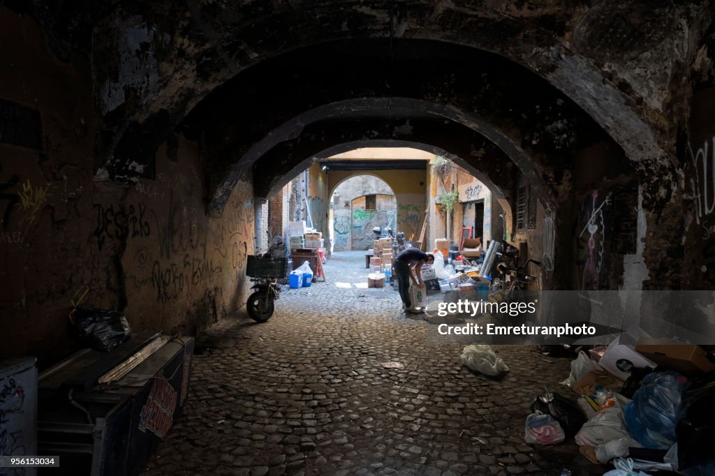 Man working in a dark,old alley in Rome.