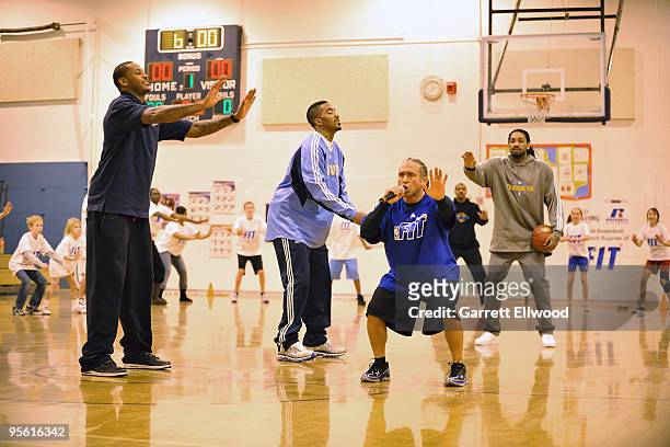 Strength and conditioning coach Steve Hess, Carmelo Anthony, J.R. Smith and Renaldo Balkman of the Denver Nuggets lead students in a stretch at West...