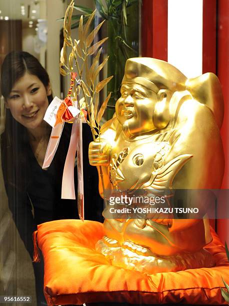 An Tanaka Kikinzoku Jewelry employee looks at a pure gold made statue of "Ebisu", 40cm tall and weighing 15kg, one of seven popular gods looked upon...