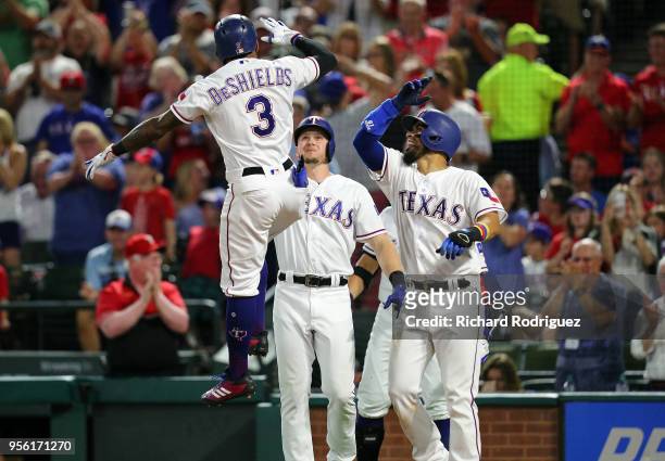 Delino DeShields of the Texas Rangers leaps in the air as he is greeted by Ryan Rua and Robinson Chirinos after a three-run home run in the fifth...