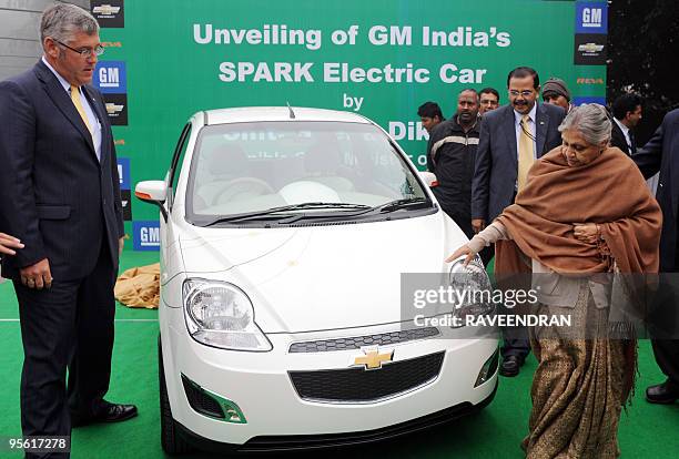 Delhi Chief Minister Sheila Dixit unveils the E-Spark electric car as President and Managing Director of GM India, Karl Slym looks on during a launch...