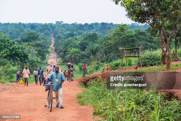 menschen vor ort zu fuß auf eine unbefestigte landstraße, dr congo - kongo stock-fotos und bilder