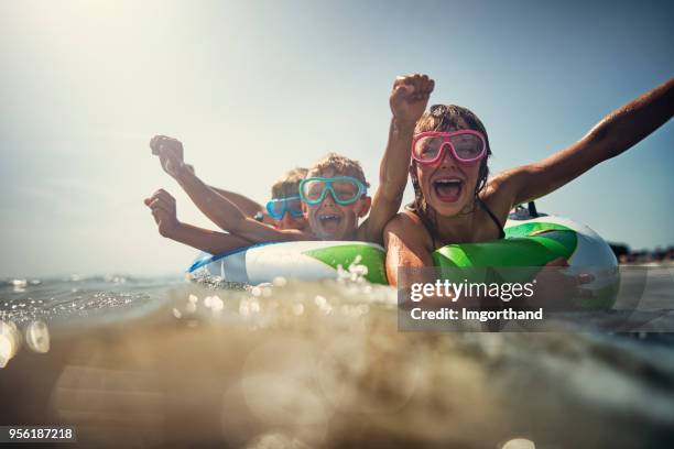 kids enjoying beach and sea vacations - inflatable ring stock pictures, royalty-free photos & images