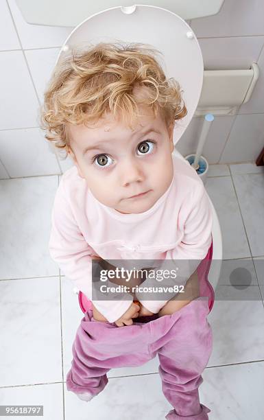 baby girl sitting on the toilet - baby pee stockfoto's en -beelden