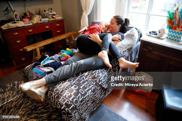 a mother and daughter with cancer happily embrace one another on the couch, in the living room. - lying on back girl on the sofa imagens e fotografias de stock