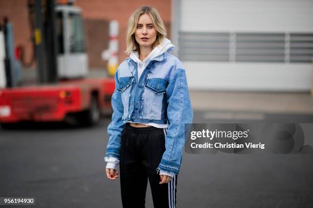 Lisa Hahnbueck wearing cropped Xsenia Schneider denim jacket, black Adidas track pants, cropped hoody, white Edited laced boots on May 3, 2018 in...