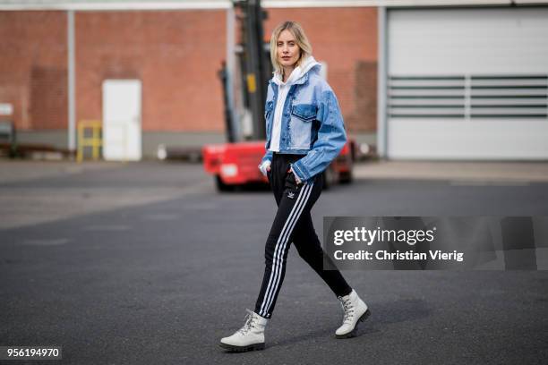 Lisa Hahnbueck wearing cropped Xsenia Schneider denim jacket, black Adidas track pants, cropped hoody, white Edited laced boots on May 3, 2018 in...