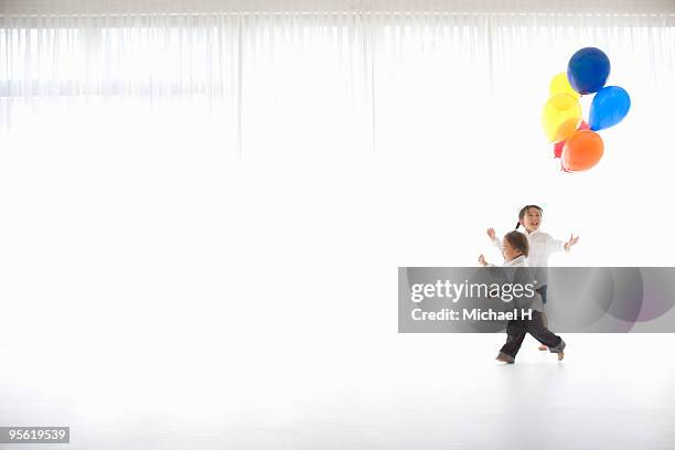 the boy and the girl are running with the balloon - child balloon studio photos et images de collection
