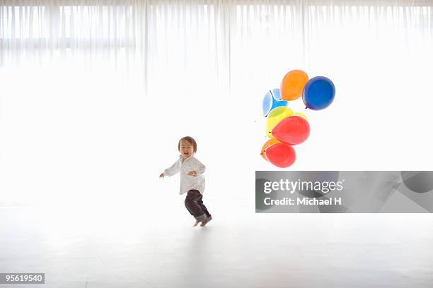 the boy who has the balloon is running - child balloon studio photos et images de collection