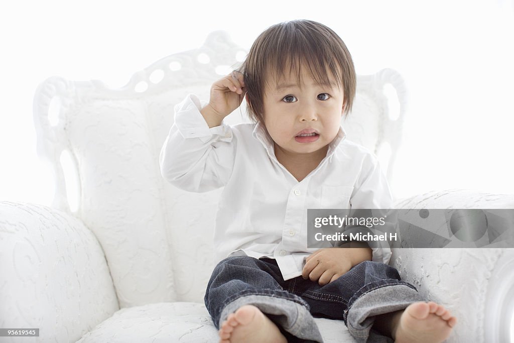 The boy is sitting on a white chair