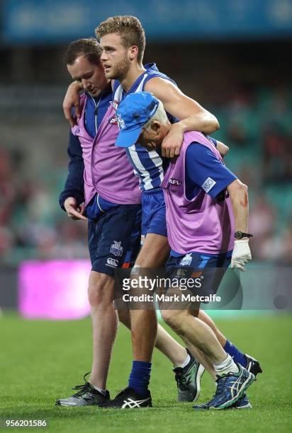 Ed Vickers-Willis of the Kangaroos is helped from the field after injuring his leg in a collision with the posts during the round seven AFL match...
