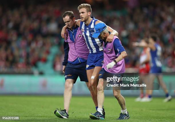 Ed Vickers-Willis of the Kangaroos is helped from the field after injuring his leg in a collision with the posts during the round seven AFL match...