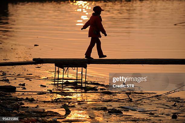 Young Chinese girl walks off a boat as the annual dry winter season caused the water level along the Yangtze river to be so low, preventing fishermen...