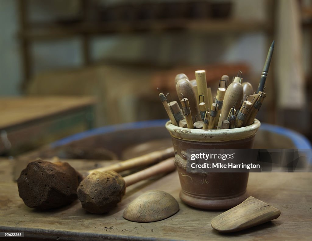 A close up of a potter's tools on a work bench